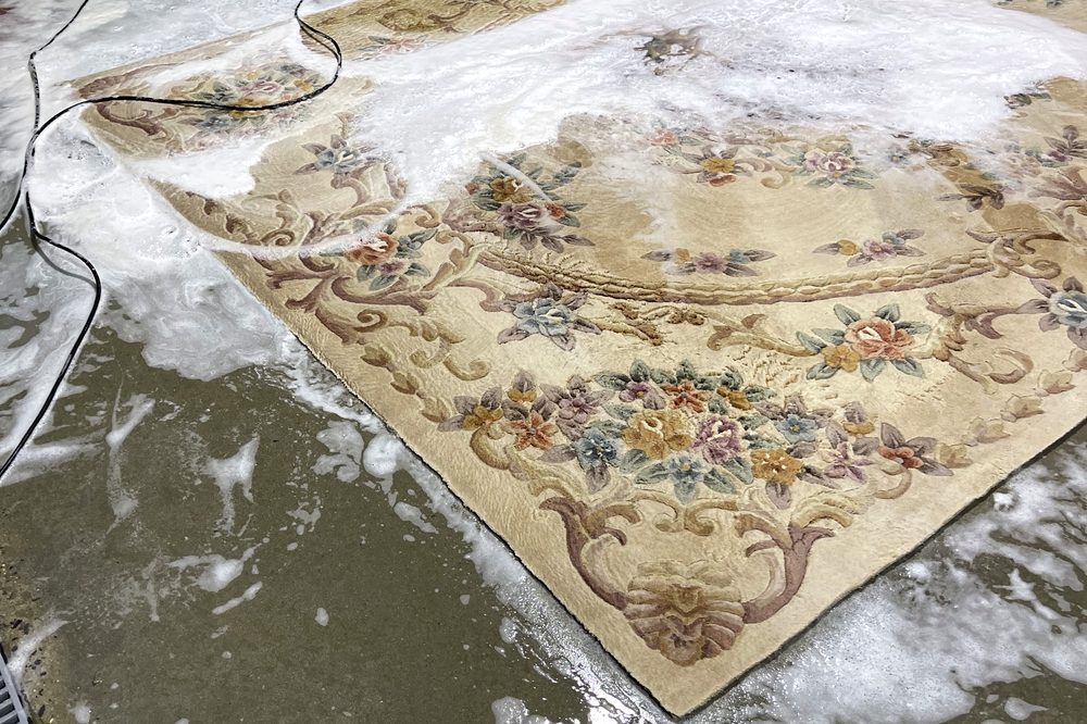 Dr Carpet technician deep-cleaning an ornate rug with a controlled wash inside the professional facility